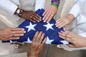 This folded flag represents the service of our sons who gave their lives for this Country and the flag is being held by different shades of hands that represent the Veterans who have served our Country, the active duty service members who are currently serving and the fallen sons and daughters of our Country.