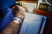 Steve 'Red Man' Flegal, a Vietnam Vet signs the guest register book.  He has been wearing Major Louis Fulda Guillermin's wrist band for too many years.  He then placed it inside the Major's coffin.