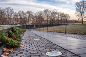 Walking through this park-like area, the memorial appears as a rift in the earth, a long, polished, black stone wall, emerging from and receding into the earth. Approaching the memorial, the ground slopes gently downward and the low walls emerging on either side, growing out of the earth, extend and converge at a point below and ahead. Walking into this grassy site contained by the walls of the memorial we can barely make out the carved names upon the memorial's walls. These names, seemingly infinite in number, convey the sense of overwhelming numbers, while unifying these individuals into a whole.