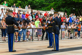 The relief commander orders the relieved sentinel, "Pass on your orders." The current sentinel commands, "Post and orders, remain as directed." The newly posted sentinel replies, "Orders acknowledged," and steps into position on the black mat.