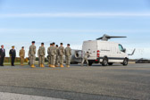Mortuary vehicle driver starts engine, and Security Forces vehicle moves into escort position in front.
