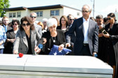 Jean Roman places a blue carnation on her brother Michael’s casket