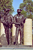 These two central figures represent two Australian soldiers facing the east and the rising sun, and represent the importance of support and comradeship represented in the Australian term, 'mates'. They wear the distinctive Australian slouch hat that carries the 'Rising Sun' badge. The figures stand on a raised podium paved in a radial pattern which refers to the Army insignia. Seven pillars represent the seven major conflicts in which the Australian Army was involved during the 20th century. They are surrounded by water, symbolic of the long sea journeys involved in Australian campaigns.