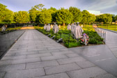 The memorial is in the form of a triangle intersecting a circle. Walls: 164 feet long, 8 inches thick; more than 100 tons of highly polished "Academy Black" granite from California: more than 2,500 photographic, archival images representing the land, sea and air troops who supported those who fought in the war are sandblasted onto the wall. Within the walled triangle are 19 stainless steel statues designed by Frank Gaylord, each larger than life-size, between 7 feet 3 inches and 7 feet 6 inches tall; each weighs nearly 1,000 pounds. The figures represent a squad on patrol, drawn from each branch of the armed forces; fifteen of the figures are from the U.S. Army, two are from the Marine Corps, one is a Navy Corpsman, and one is an Air Force Forward Air Observer. They are dressed in full combat gear, dispersed among strips of granite and juniper bushes which represent the rugged terrain of Korea. When reflected in the pool, there appears to be 38 soldiers, representing the 38th parallel. To the north of the statues is a path, forming one side of the triangle.