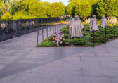 Behind, to the south, is a 164 foot-long black granite wall, created by Louis Nelson, with photographic images sandblasted into it depicting soldiers, equipment and people involved in the war. This forms the second side of the triangle. The third side of the triangle, facing towards the Lincoln Memorial, is open.