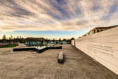 The urban grove makes up over two-thirds of the 2.4-acre triangular site. Other landscaping features include clipped evergreen hedges that parallel the laminated glass panels, and fragrant shrubs.